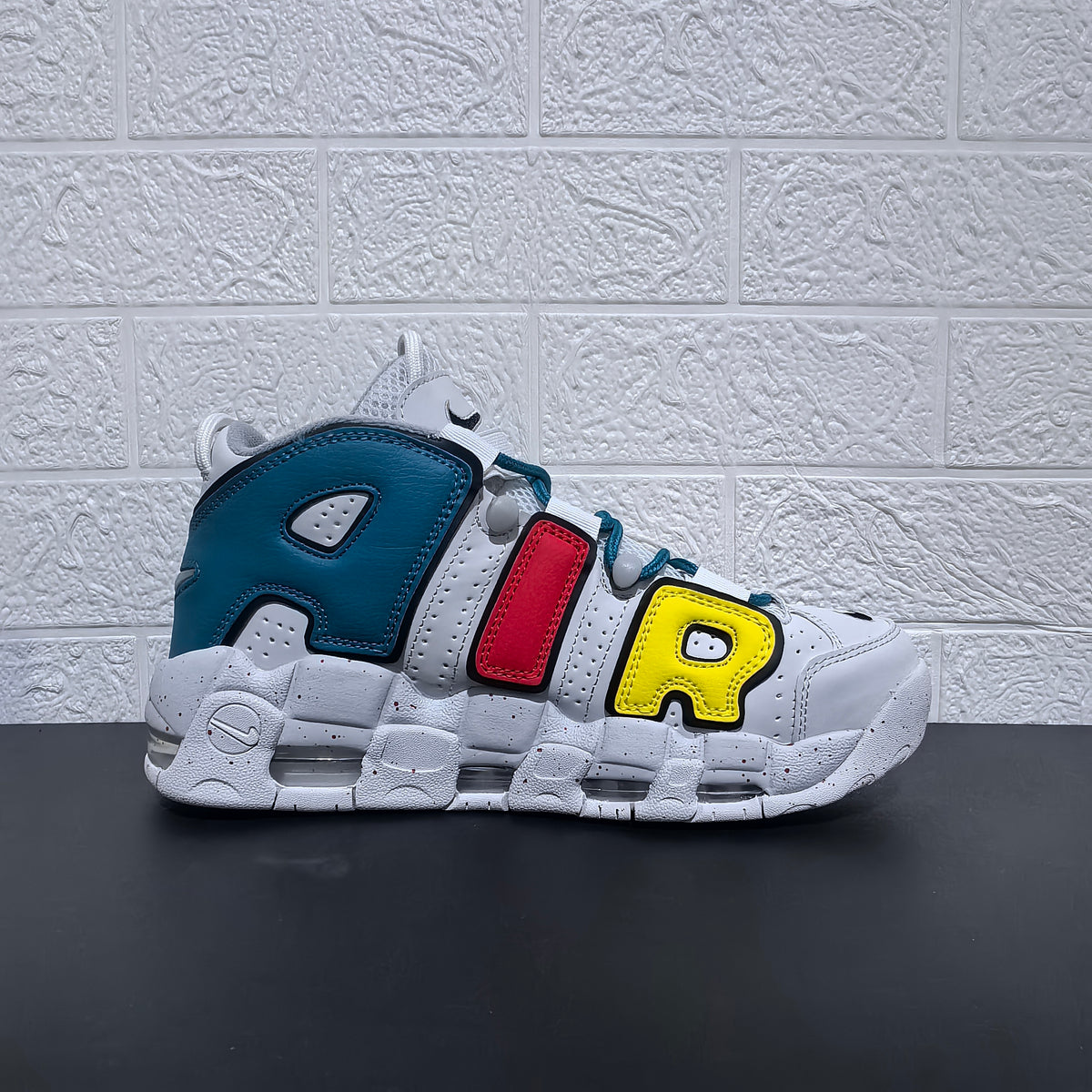 Side profile of a sneaker with oversized AIR lettering in red, yellow and blue