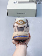 Rear view of a beige and taupe sneaker with a purple heel accent