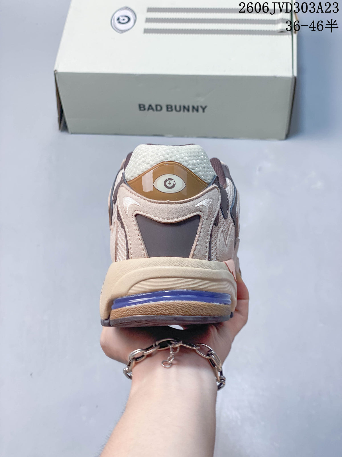 Rear view of a beige and taupe sneaker with a purple heel accent