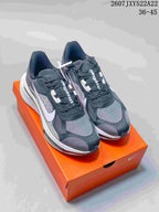 Pair of black, gray, and white Nike running shoes displayed on an orange shoebox