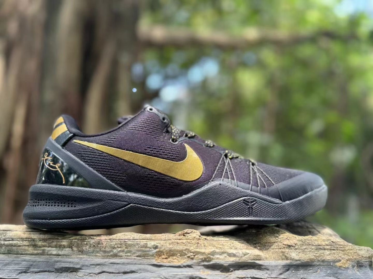 Side profile of a black sneaker with a gold Swoosh, gold-accented laces, and a textured midsole.