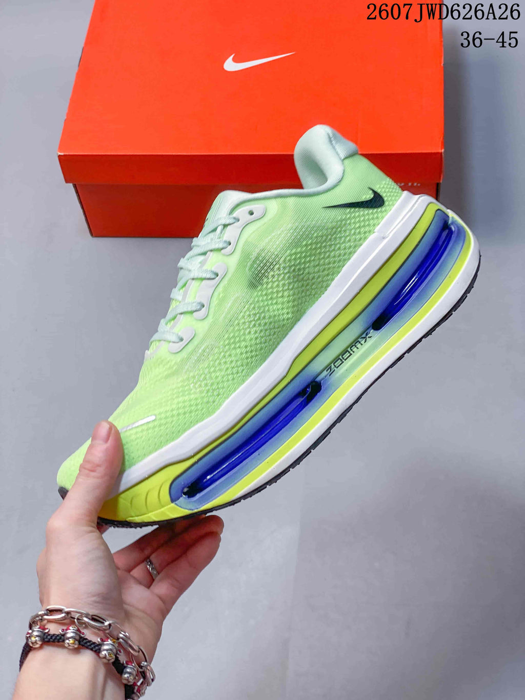Side view of a green Nike sneaker showing the textured upper, black Swoosh, and blue cushioning elements.
