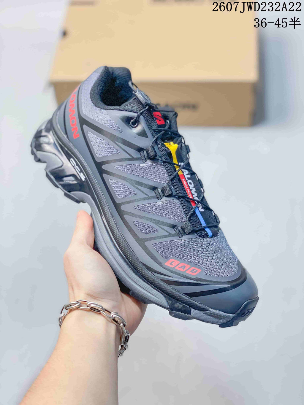 Angled side view showing the gray and black upper, red Salomon branding, layered side panels, and rugged outsole.