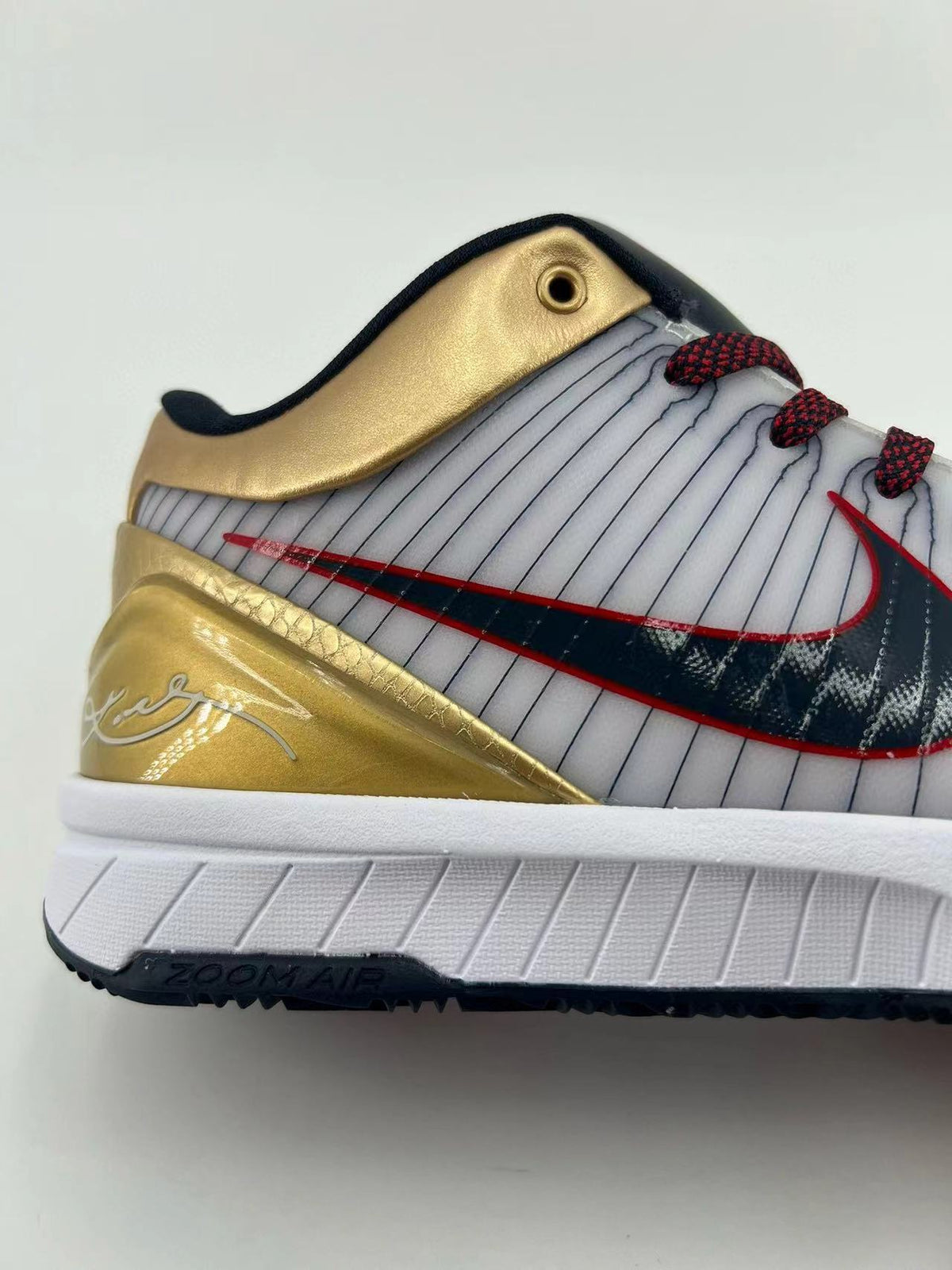 Close-up of the gold heel overlay, striped upper, and side logo.