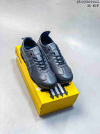 Pair of black Onitsuka Tiger low-top sneakers displayed on a yellow shoebox, with style code 2510JGD291A22 and a size range visible above.