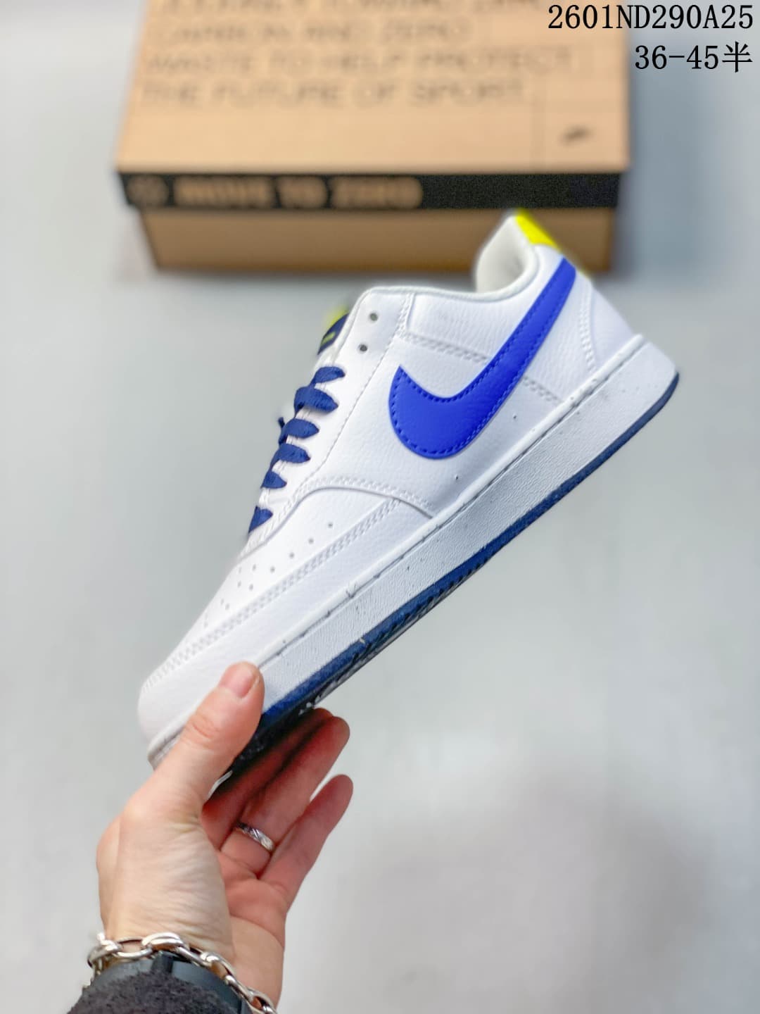 Side view showing the white low-top upper, blue Swoosh, blue outsole edge, and yellow heel accent.