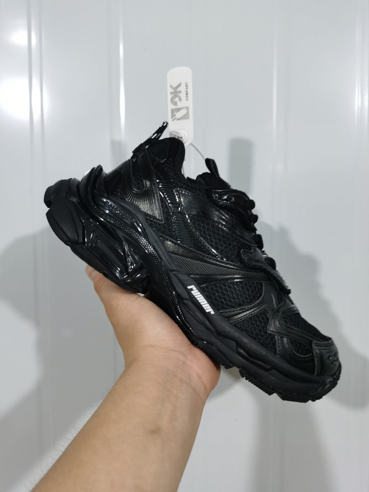 Angled top view of the black Puma sneaker showing the lacing, mesh panels, tonal overlays, and textured outsole.