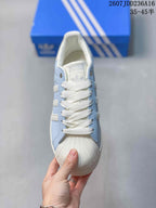 Top view showing white laces, light blue panels, adidas tongue branding, and textured toe cap.