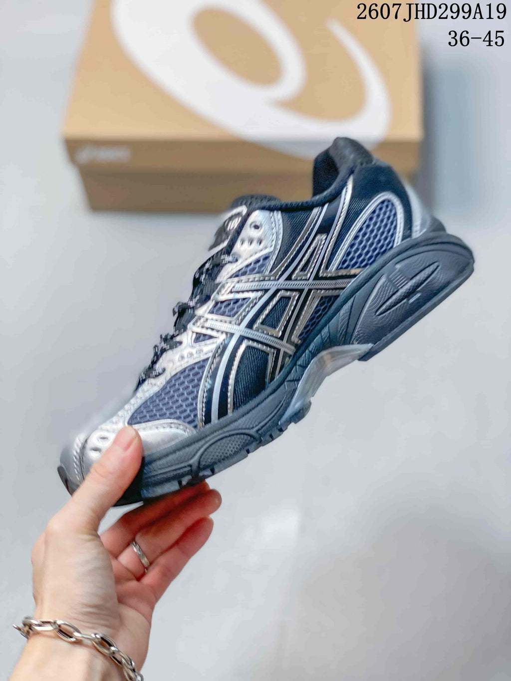 Side profile of the black and silver ASICS sneaker showing mesh panels, layered side branding, padded collar, and thick outsole.