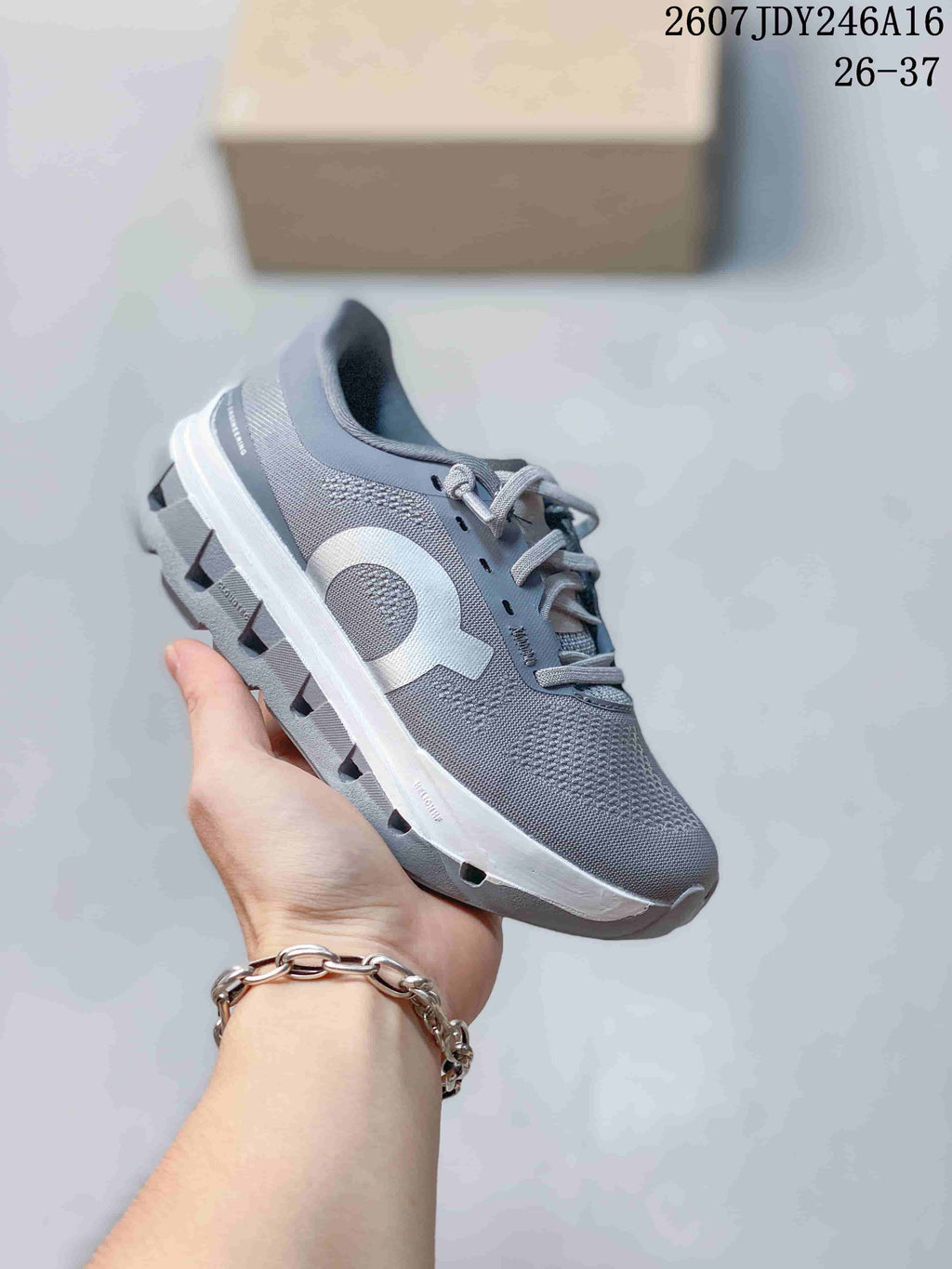 Gray On Cloudstratus 3 kids running shoe held at an angle, showing the textured upper, side logo and segmented outsole.