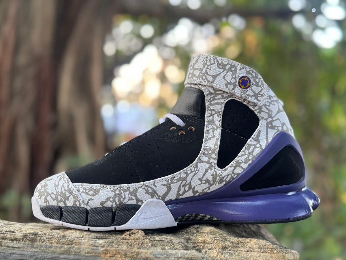Angled front and side view showing the black upper, patterned overlays, and ankle strap