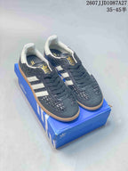 Pair of dark navy and white adidas Originals Samba ADV sneakers displayed on a blue shoe box, with a gum-colored outsole and product code text above.