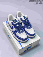 Pair of white and blue low-top sneakers displayed on a Nike shoebox, with blue patterned overlays and visible tongue branding.