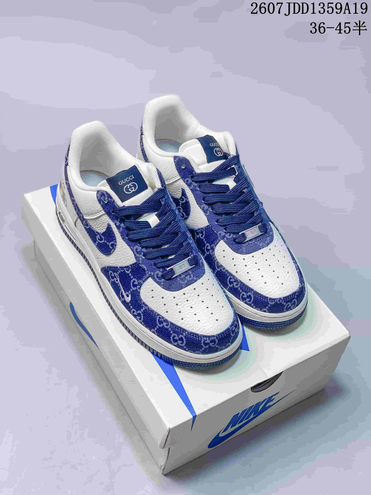 Pair of white and blue low-top sneakers displayed on a Nike shoebox, with blue patterned overlays and visible tongue branding.