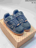 Pair of navy Louis Vuitton Trainer Maxi low-top sneakers with tan accents, shown on a patterned box