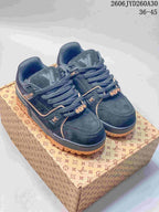 Pair of navy Louis Vuitton Trainer Maxi low-top sneakers with tan accents, shown on a patterned box