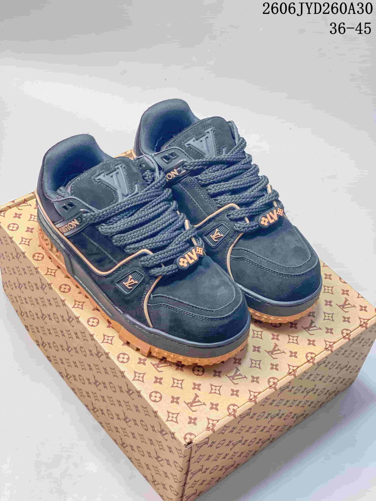 Pair of navy Louis Vuitton Trainer Maxi low-top sneakers with tan accents, shown on a patterned box