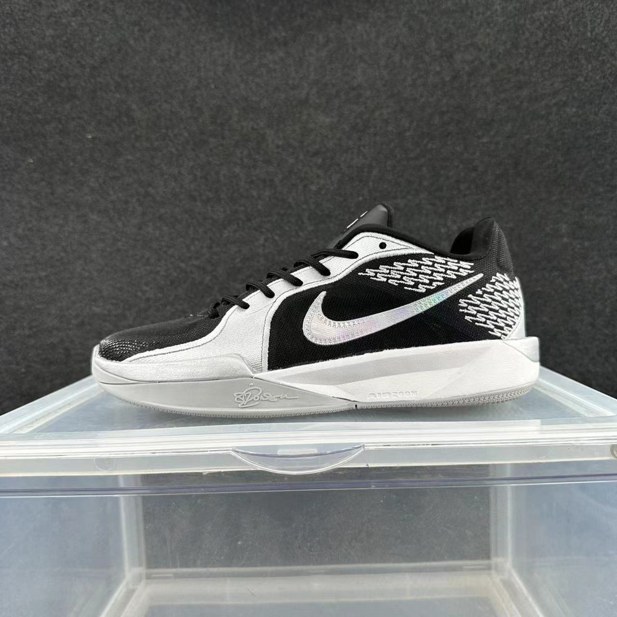 Side view of a low-cut Nike Sabrina basketball shoe in grey, silver, black, and white.