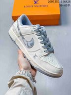 Close-up of a white sneaker with gray details, patterned accents, and gray laces.