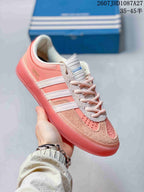 Angled side view showing the pink upper, white three stripes and low-profile sole.