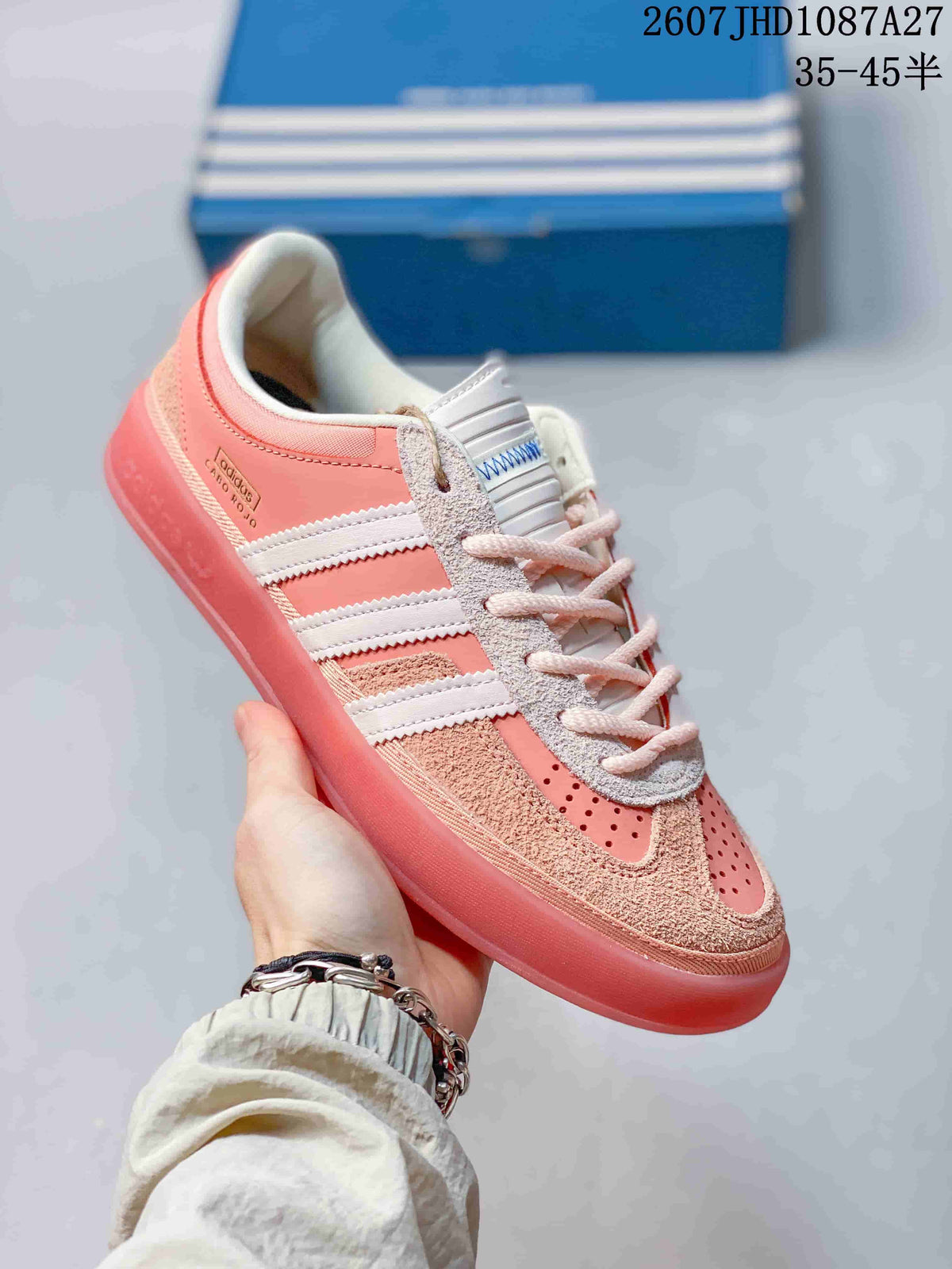 Angled side view showing the pink upper, white three stripes and low-profile sole.