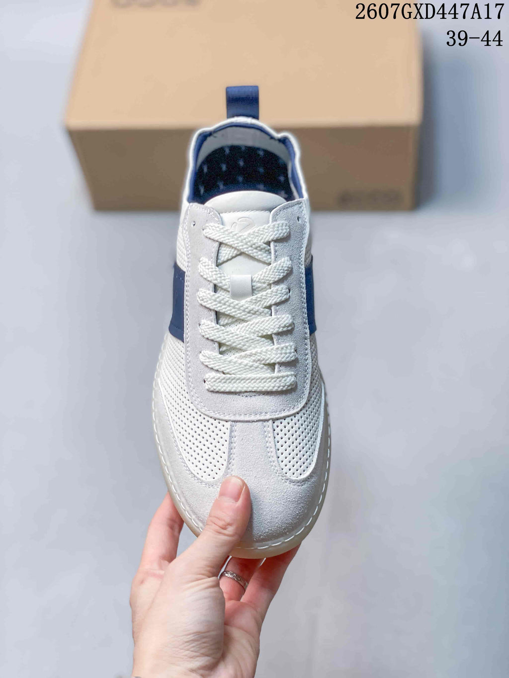 Top view of the white perforated sneaker with braided laces, blue accents, and rounded toe.