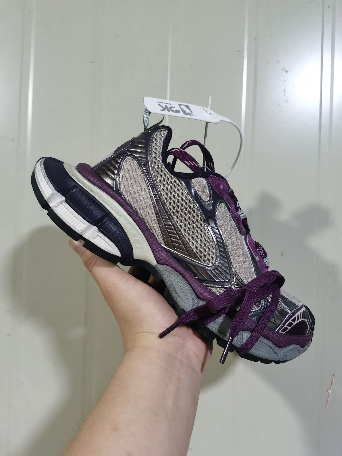 Angled view of the purple and grey Nike 1269 sneaker showing the layered upper, laces, side swoosh, and contrasting outsole sections.