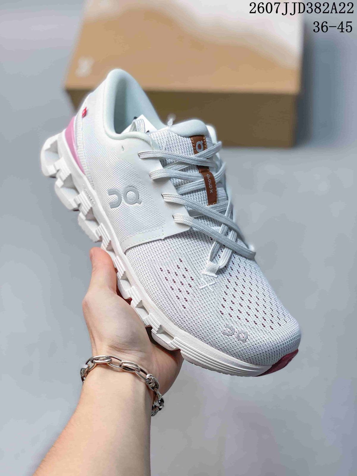 Angled side view of the white and pink On sneaker showing the knit-style upper, lace closure, On branding, and segmented outsole.