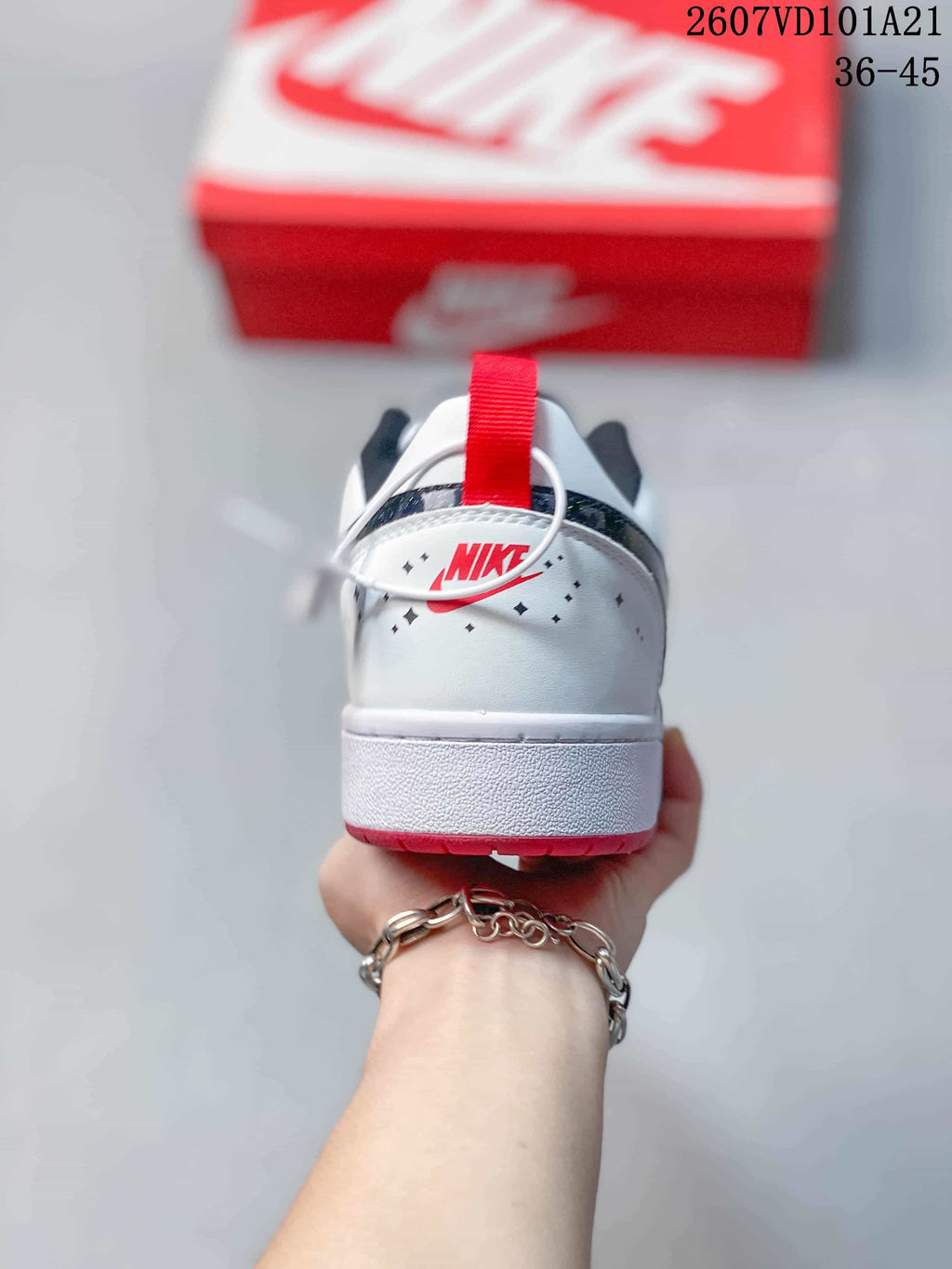 Rear view of the white sneaker showing the red heel pull tab, dark collar lining and red outsole edge.