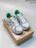 Pair of silver-toned ASICS GEL-KAYANO 12.1 shoes with green accents, viewed from above on a shoebox.