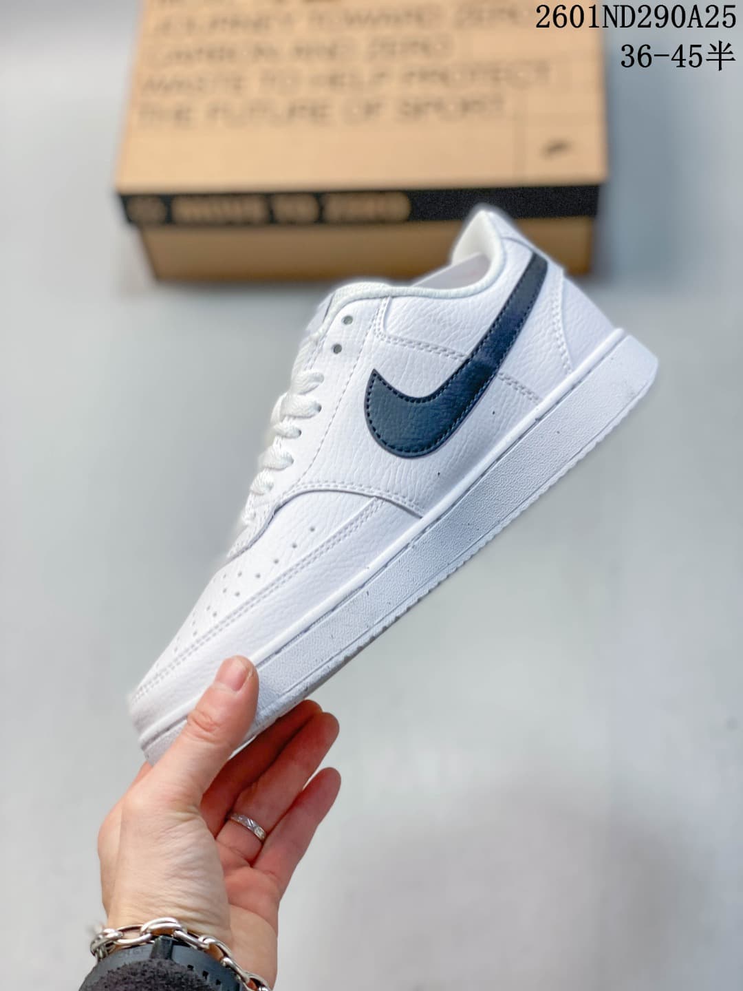 Side view of a white low-top sneaker with a dark navy Swoosh and perforated panels.