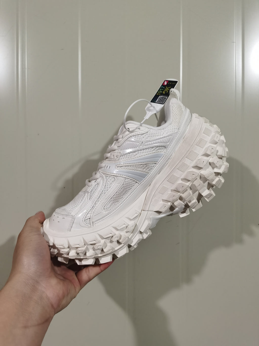 White Caterpillar Defender sneaker shown from the outer side, highlighting layered upper panels and a chunky lugged outsole.