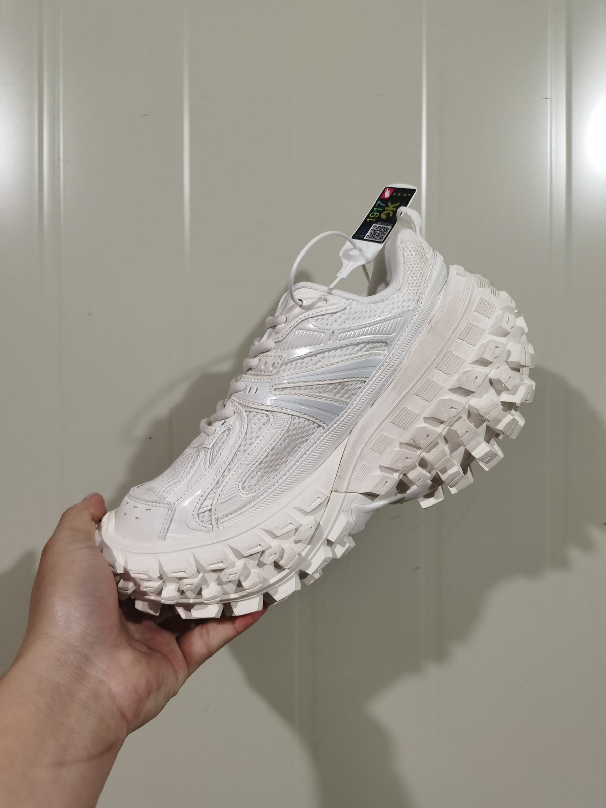 White Caterpillar Defender sneaker shown from the outer side, highlighting layered upper panels and a chunky lugged outsole.