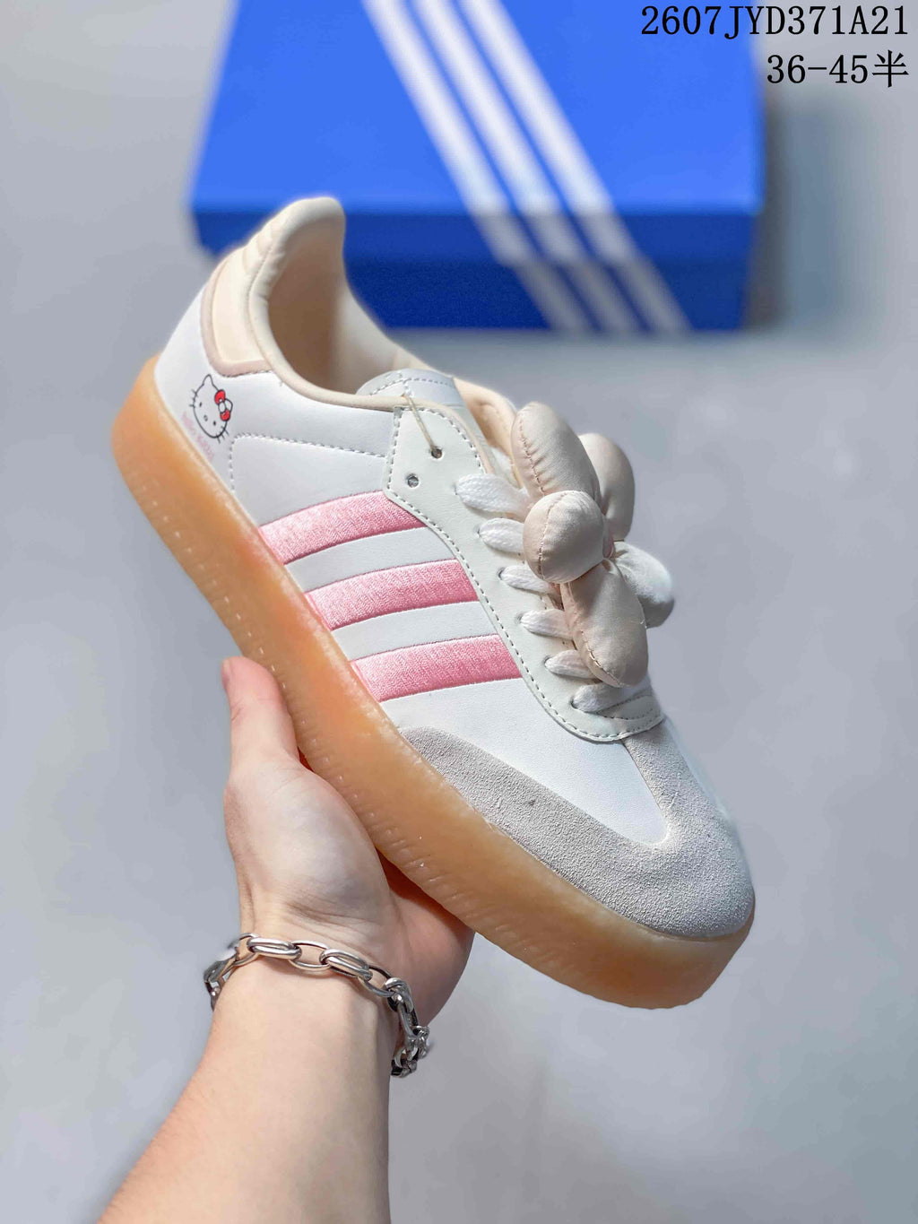 Angled side view showing the pink stripes, white upper, flower detail, Hello Kitty heel graphic, and gum sole.