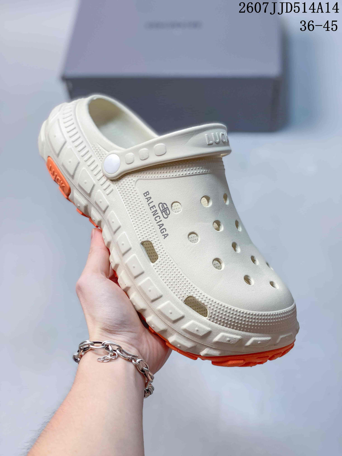 Close-up side view of a white perforated clog showing the adjustable strap, branding and chunky treaded outsole.