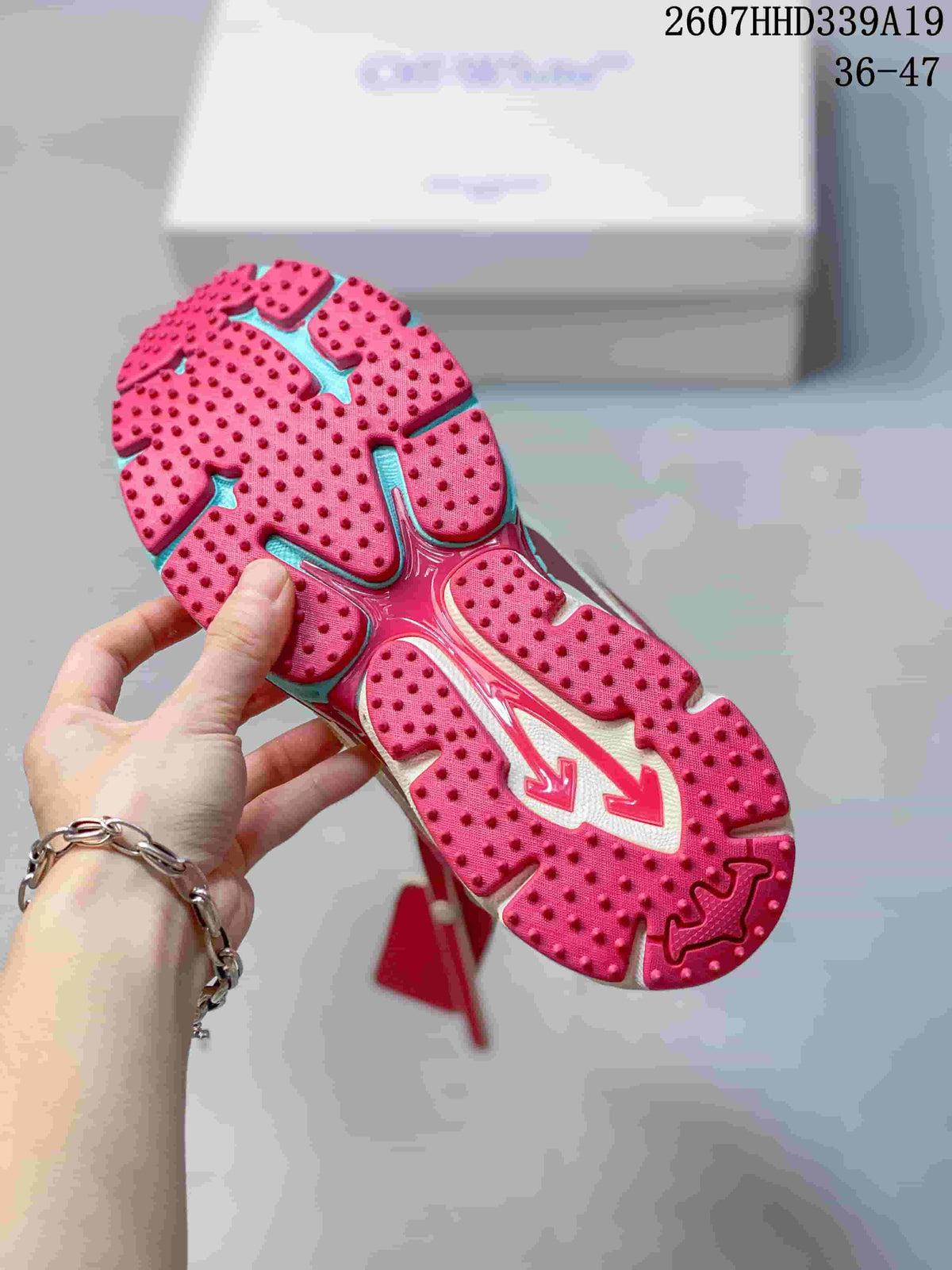 Close view of the sneaker outsole showing a red studded tread pattern with turquoise sections.