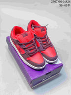 Red and dark brown Nike SB Dunk Low sneakers displayed on a purple shoebox.