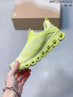 Side profile of the lime yellow sneaker showing the mesh-style upper, stitched paneling, pull tab, and segmented outsole.