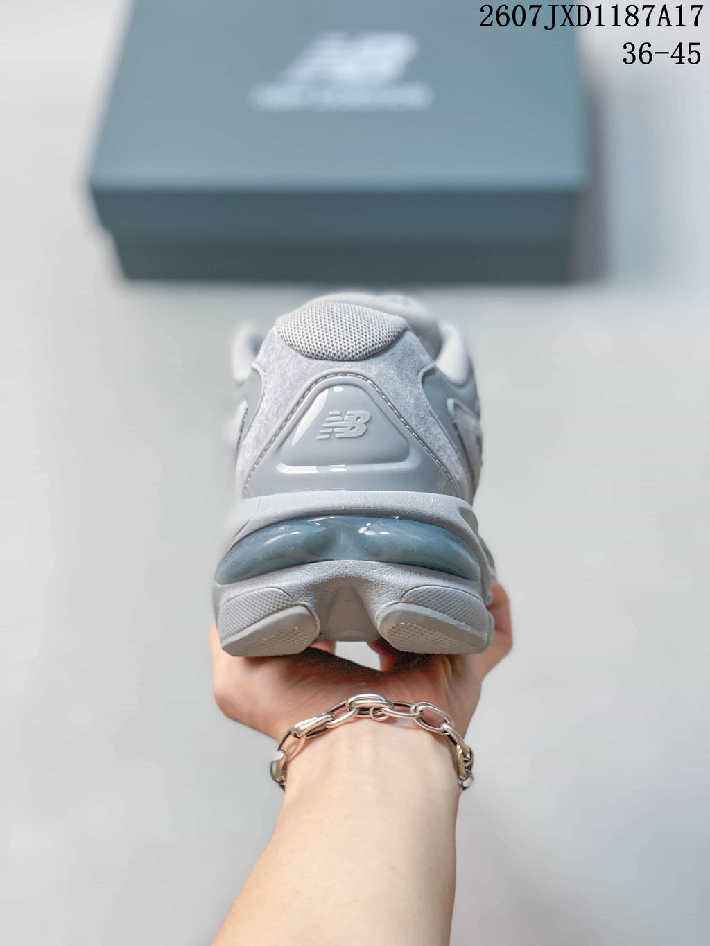 Rear view of the grey sneaker showing the padded heel, New Balance branding, and layered outsole.