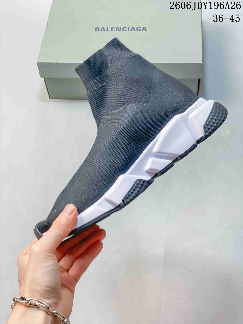 Side profile of a dark gray sock-style sneaker showing the stretch-knit upper, white sculpted midsole, and black outsole.