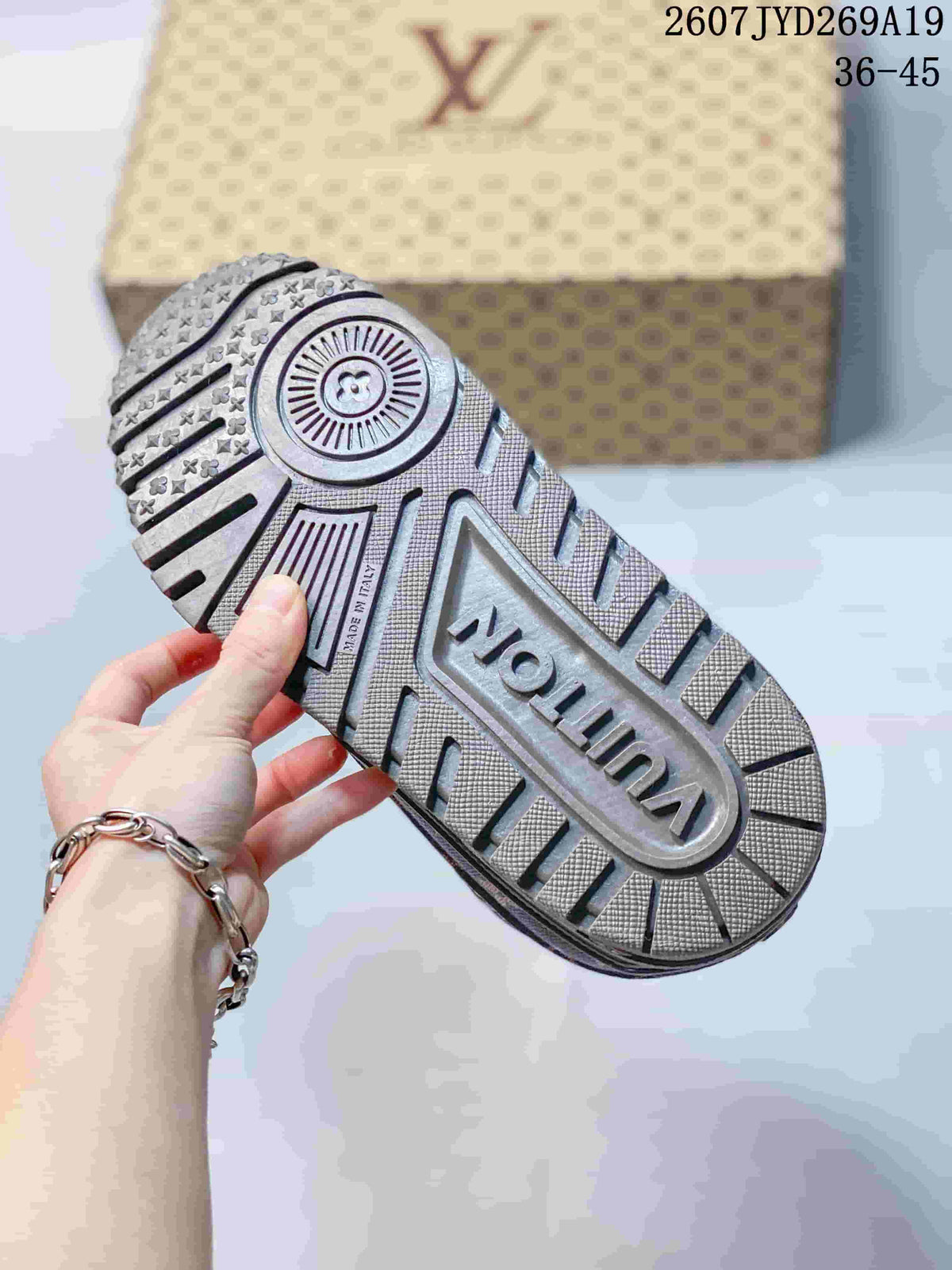 Bottom view of a sneaker showing the textured lugged outsole, circular heel detail, and central logo panel.