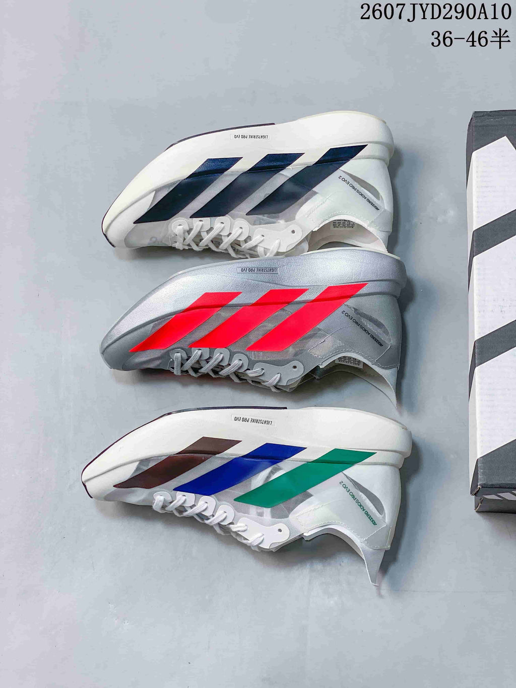 Three Adidas Adizero Adios Pro Evo 2 colorways shown together: white with dark accents, silver-gray with bright red accents, and white with blue, green and dark accents.