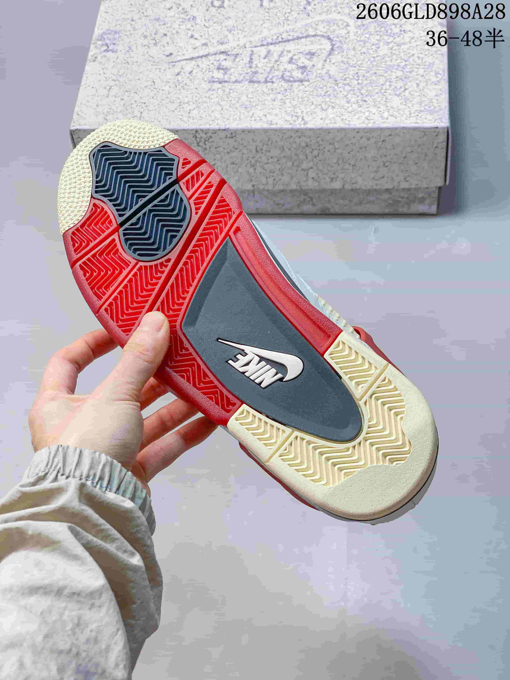 Underside of the sneaker showing a red, grey, and cream-toned patterned outsole.
