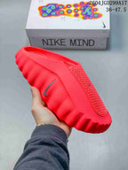 Side view of a bright red Nike Mind slide showing the perforated upper and sculpted outsole.
