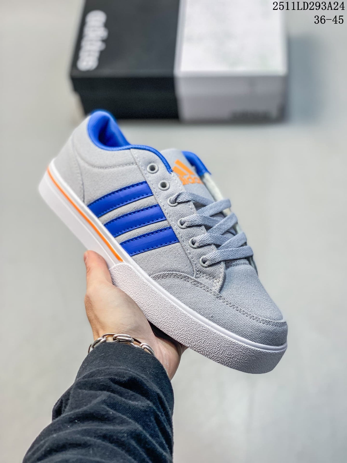 Angled side view of the grey Adidas sneaker with blue stripes, orange branding and white outsole.