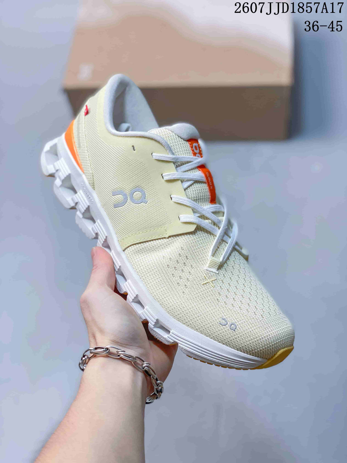 Angled side view of the cream On sneaker showing the layered upper, side branding, orange heel accent, and white outsole.