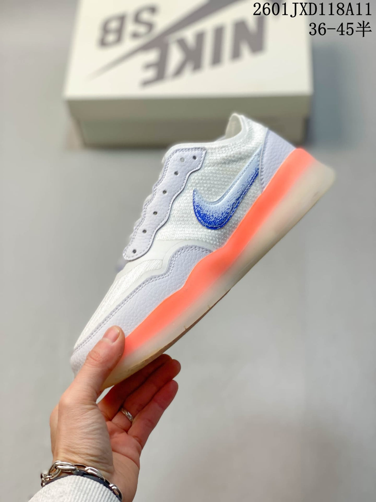 Side profile showing the white and blue upper, layered overlays, and bright orange outsole edge.
