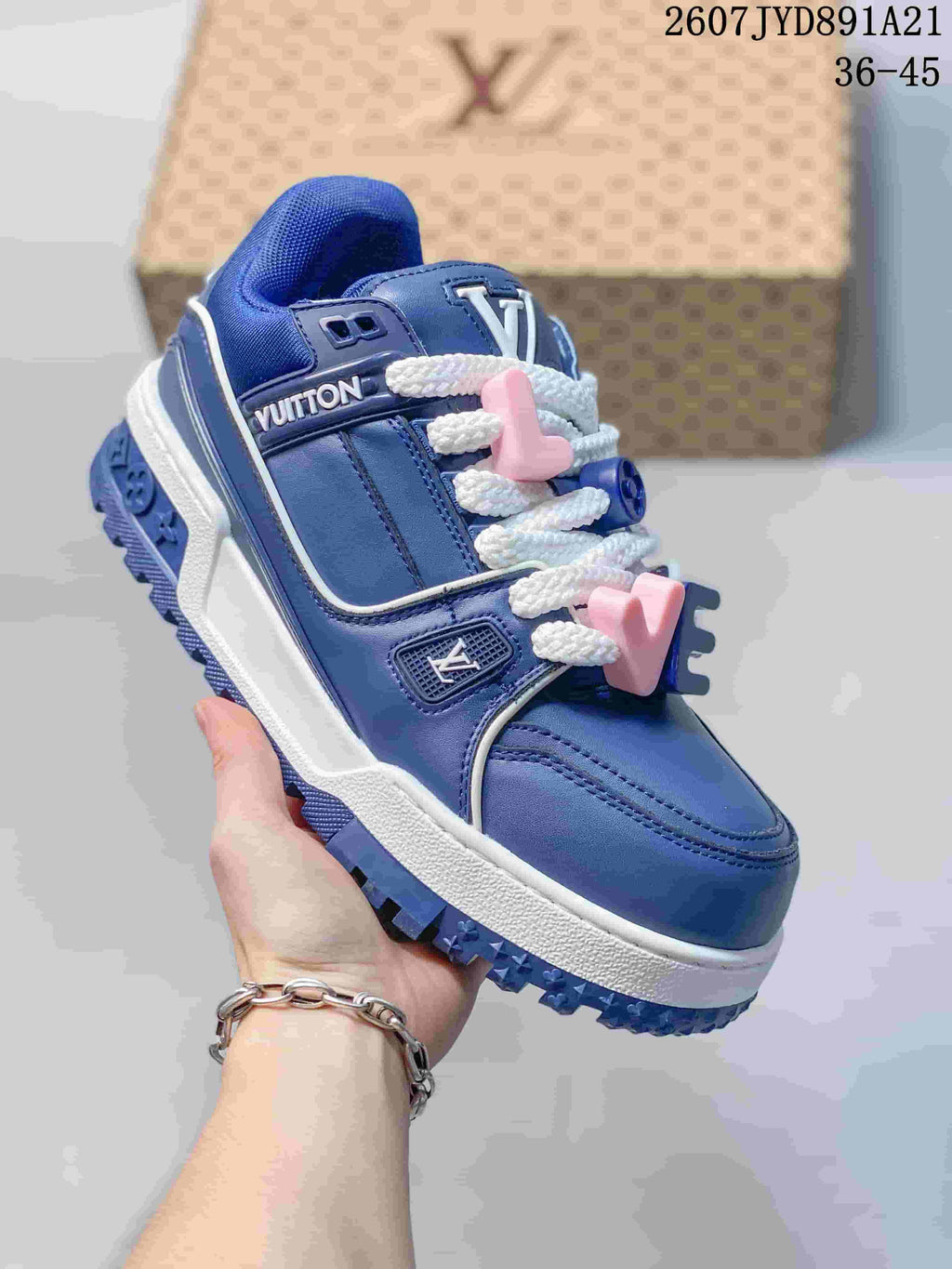 Three-quarter view of the blue low-top sneaker showing the side panels, white laces, decorative charms, and chunky sole.
