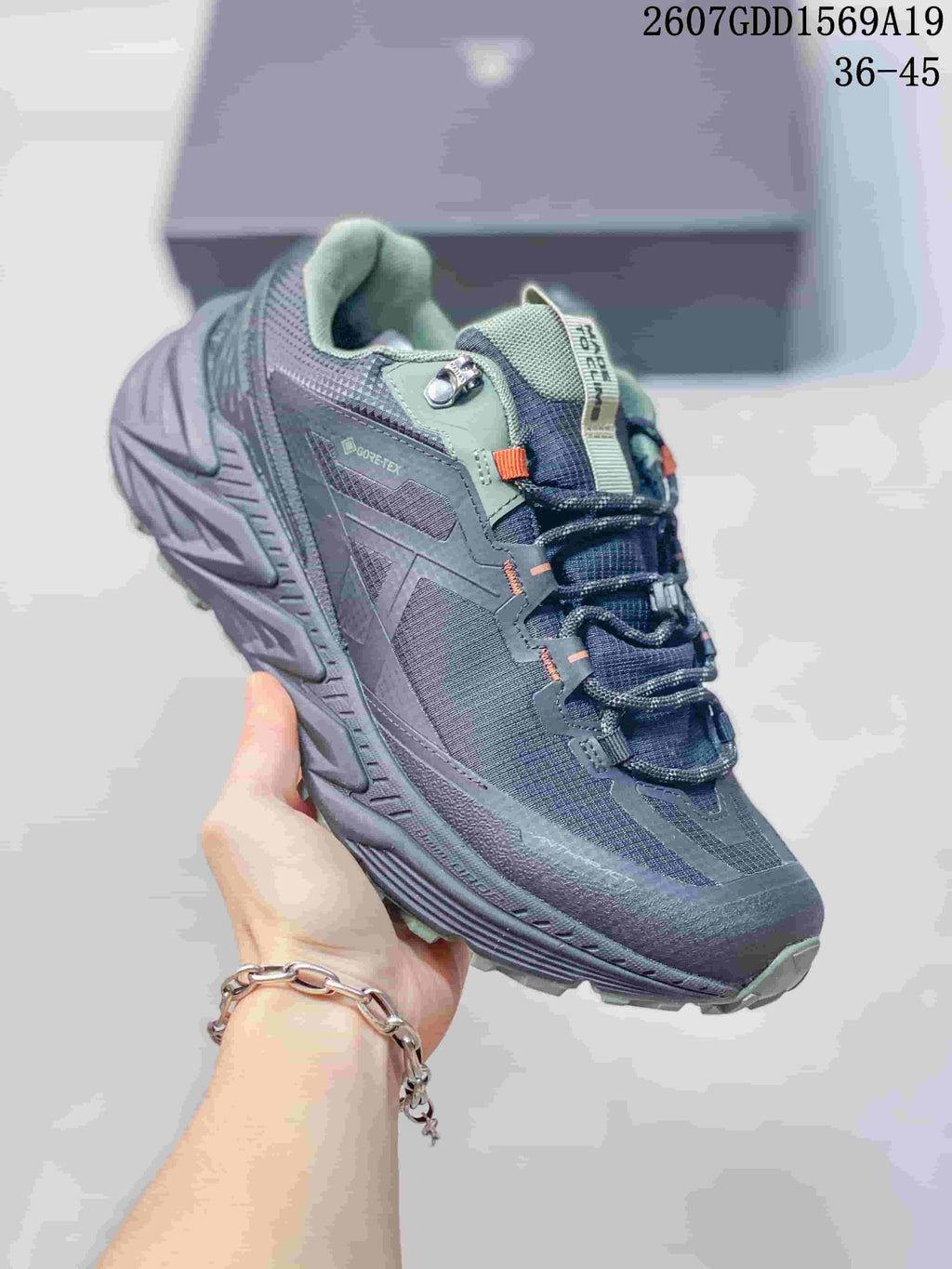 Angled side view showing the dark gray upper, sage accents, lace hardware, GORE-TEX marking, and rugged outsole.
