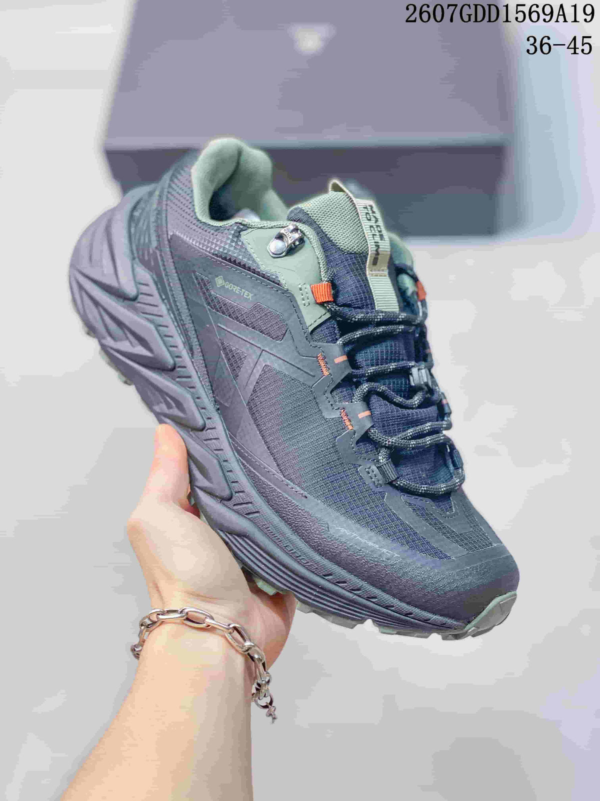 Angled side view showing the dark gray upper, sage accents, lace hardware, GORE-TEX marking, and rugged outsole.
